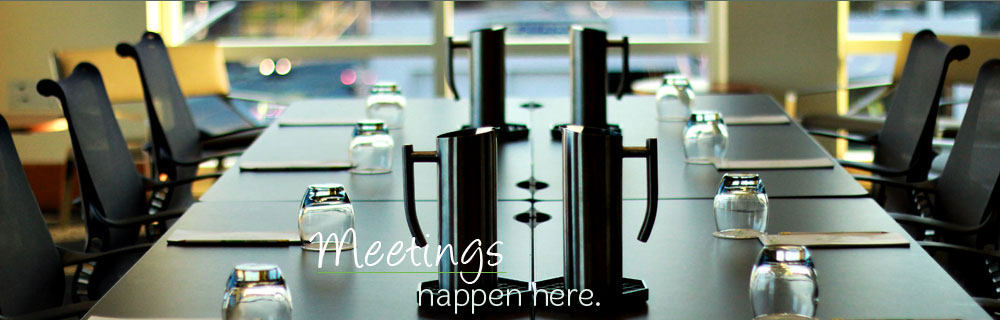 Conference table setup with chairs, water glasses, and presentation equipment
